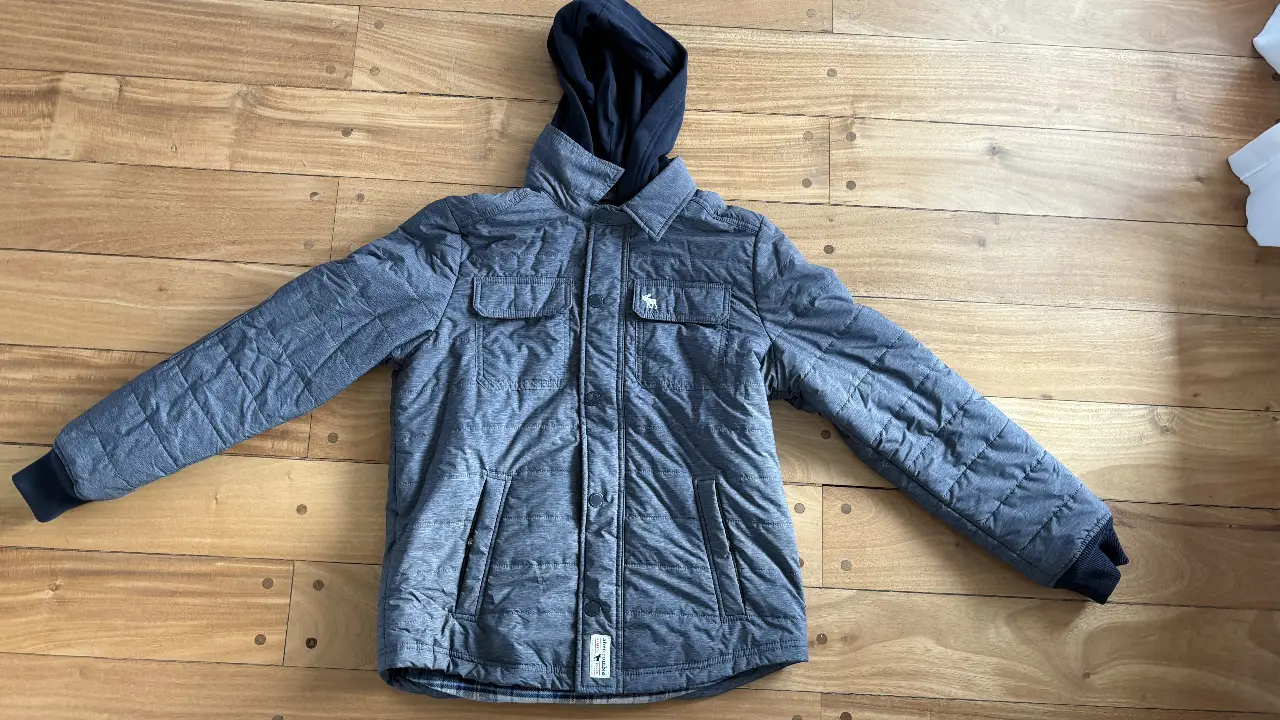 Campera acolchada para niño, con capucha de color negro y forro interior a cuadros. Ideal para el invierno.