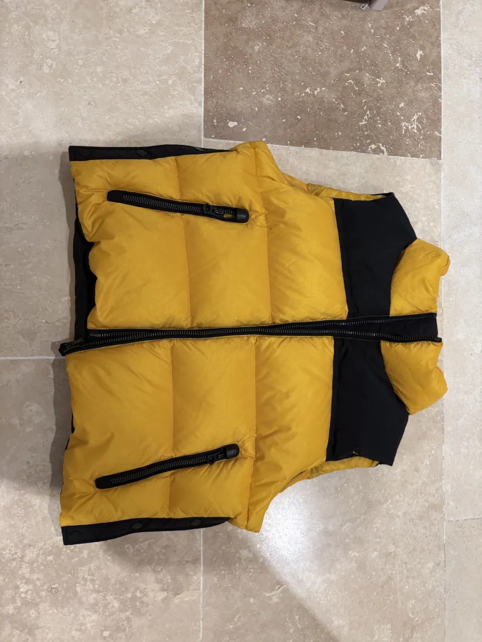 Chaleco acolchado amarillo y negro, ideal para un look urbano y moderno. Perfecto para usar en días frescos, combina estilo y comodidad.