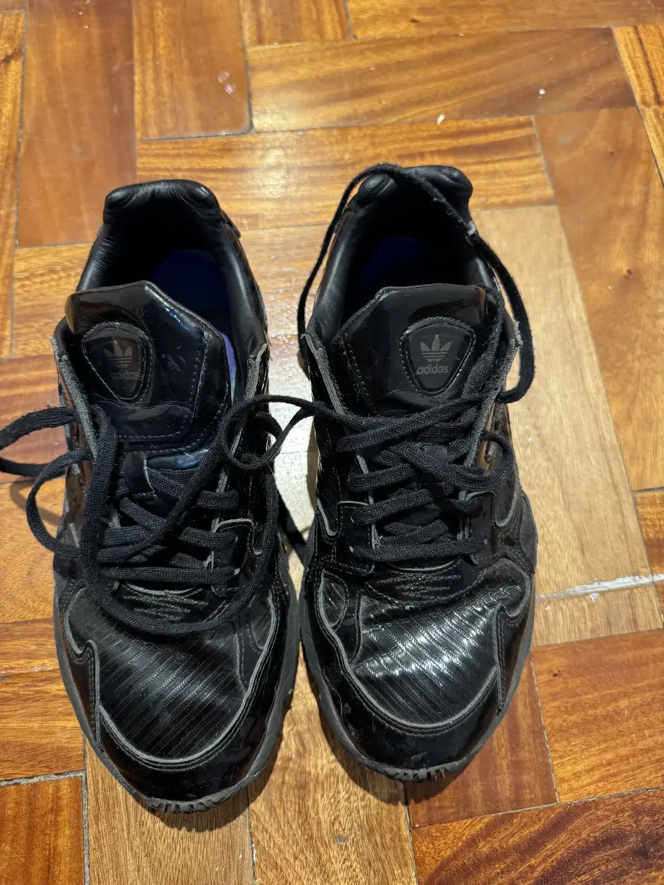Zapatillas Adidas negras, con detalles brillantes y suela gruesa. Ideales para un look urbano y moderno.