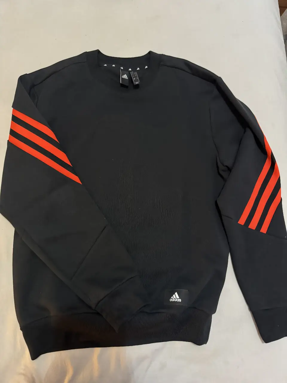 Buzo de cuello redondo Adidas para hombre, color negro con detalles en rojo en las mangas. Ideal para un look deportivo y casual.