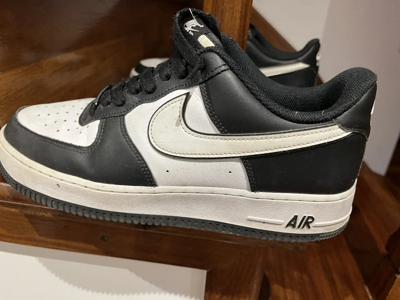 Zapatillas Nike Air Force 1, blancas con detalles en negro. Diseño clásico y atemporal, ideales para un look casual y urbano.