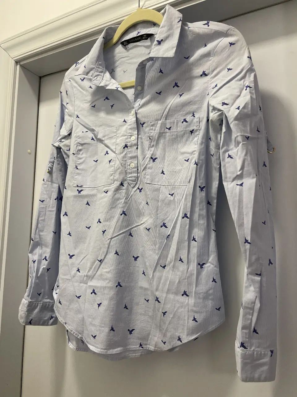 Camisa de mujer Zara Basic con estampado de pájaros en azul sobre fondo blanco. Corte clásico, con cuello camisero y mangas largas. Ideal para un look casual y fresco.