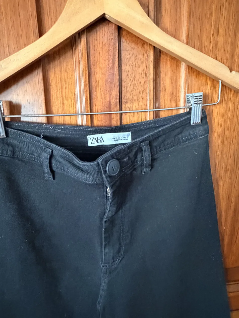 Pantalón de jean negro con bolsillos traseros y detalle de dobladillo deshilachado en los botamangas. Tiro alto.