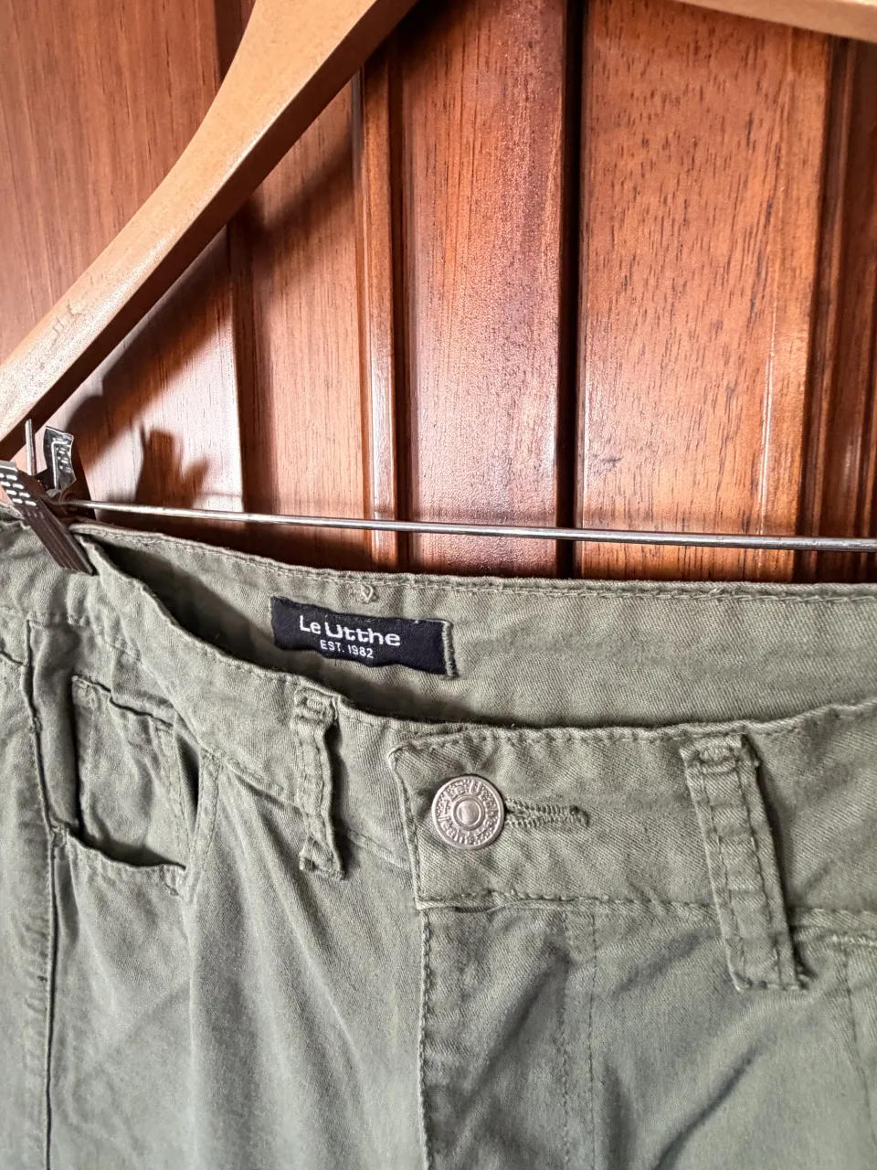 Pantalón cargo color verde militar. Posee bolsillos frontales y laterales con tapa. Cierre y botón en la parte delantera.