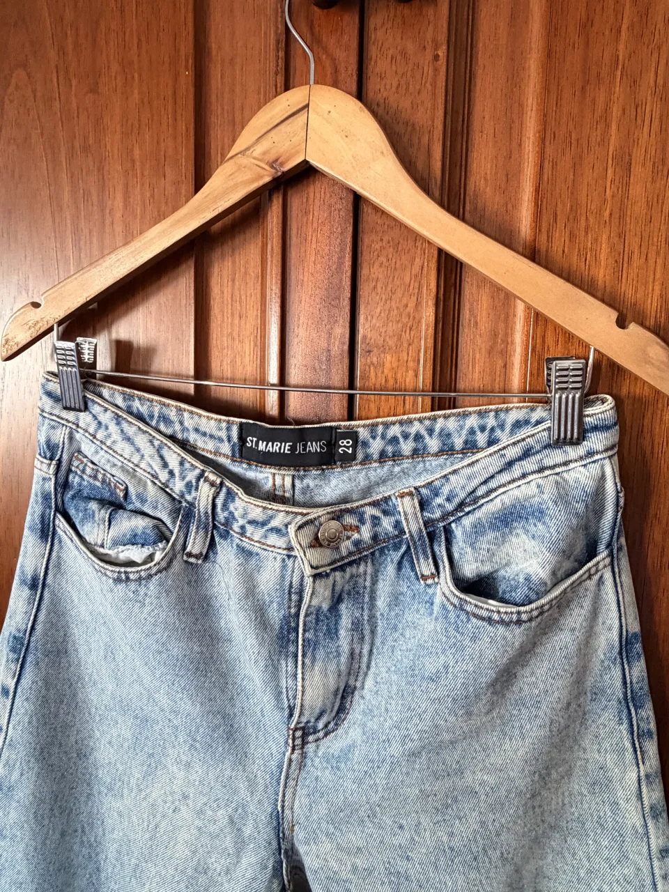 Jeans tiro alto con lavado claro y roturas desflecadas en los tobillos. Modelo de cinco bolsillos con cierre y botón.