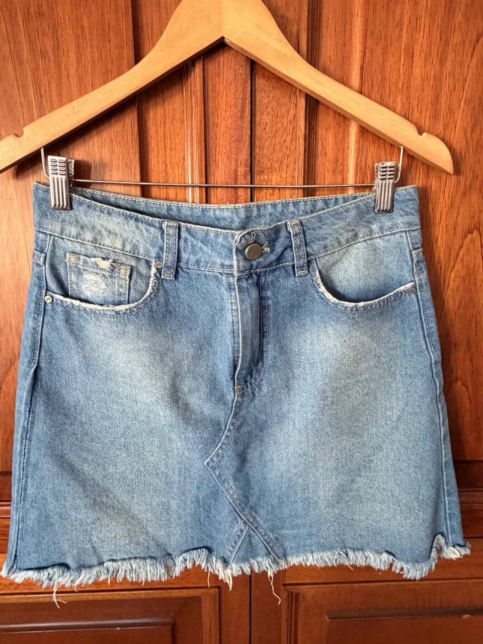 Pollera de jean corta con roturas y detalles deshilachados en los bordes. Tiene bolsillos delanteros y traseros.