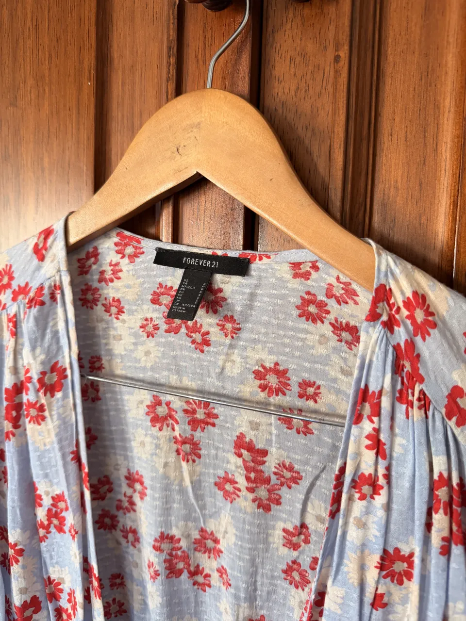 Blusa Forever 21 con estampa floral de flores rojas y blancas sobre fondo celeste. Posee elástico en la cintura y puños con volados.