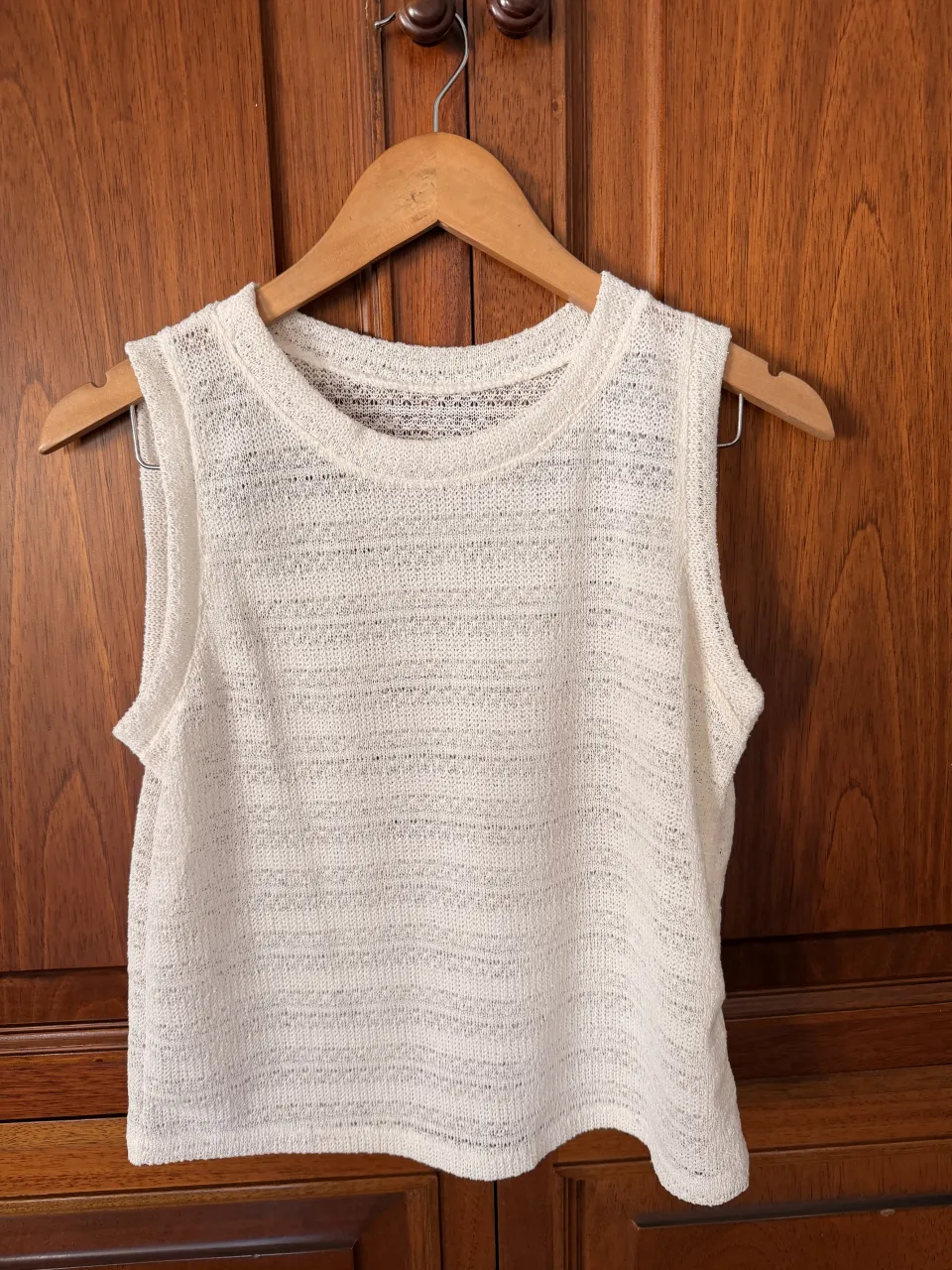 Remera blanca de tejido fino, sin mangas y cuello redondo. 