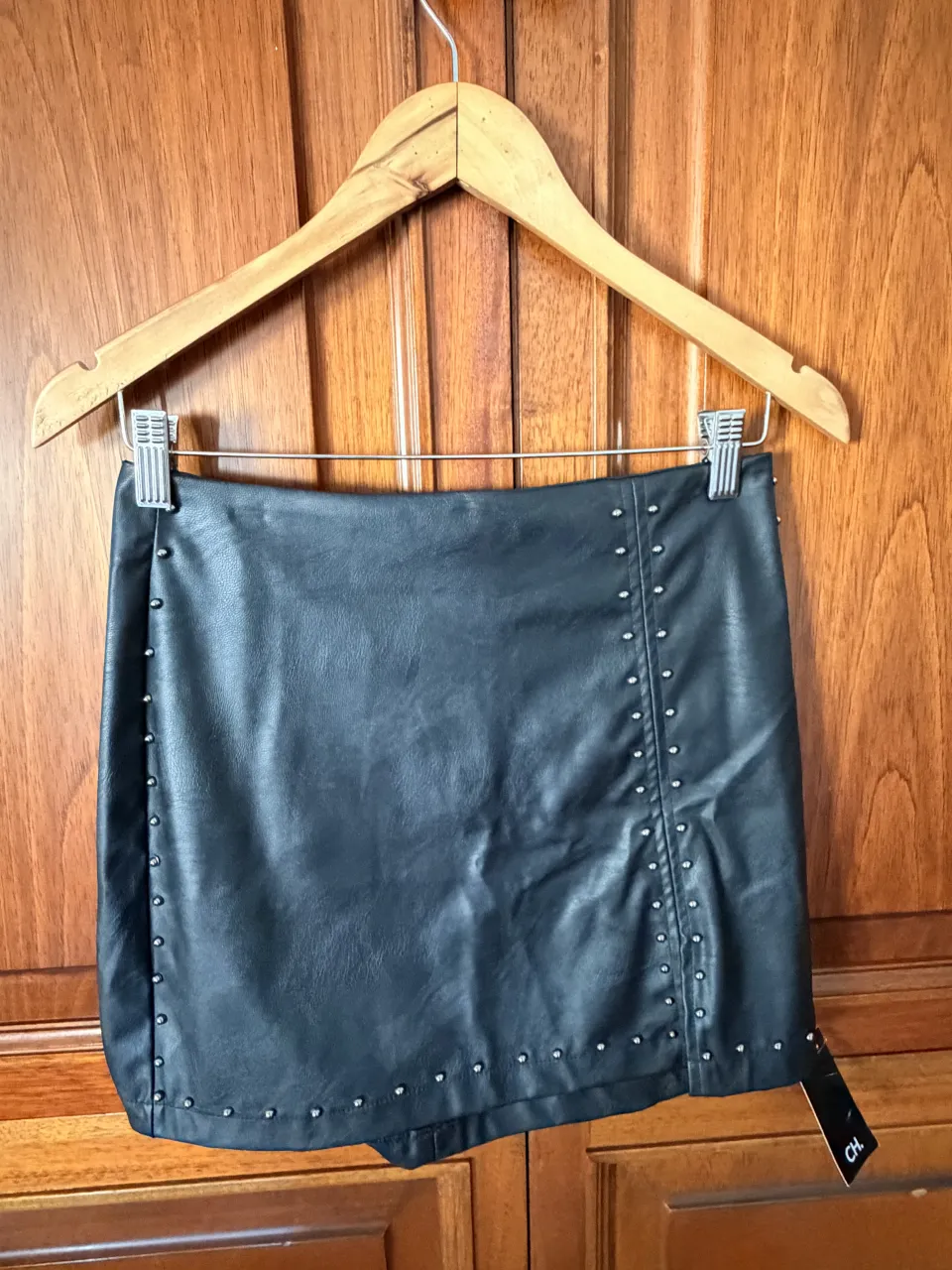 Pollera negra corta con tachas plateadas alrededor del borde inferior y en el lateral izquierdo. Tiene una abertura en el lateral izquierdo.