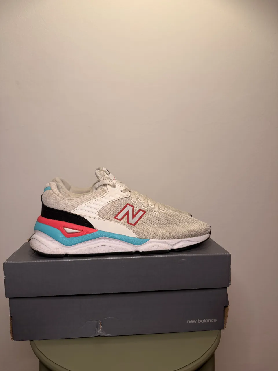 Zapatillas deportivas blancas con detalles en rojo, negro y turquesa. Logo de la marca en los laterales.