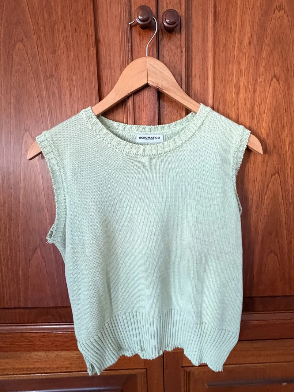 Chaleco de tejido de punto sin mangas, color verde pálido. Posee cuello redondo y terminación de puño en la cintura.