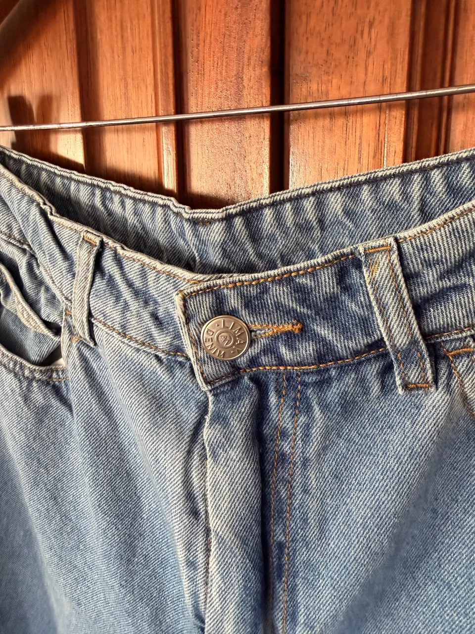 Jeans de tiro alto con cierre y botón metálico. Posee bolsillos delanteros y traseros.