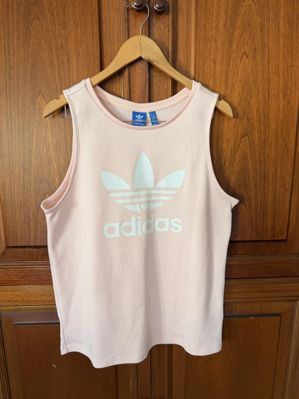 Musculosa deportiva Adidas color rosa pastel con logo grande de Adidas en blanco en el frente. Escote redondo y sin mangas.
