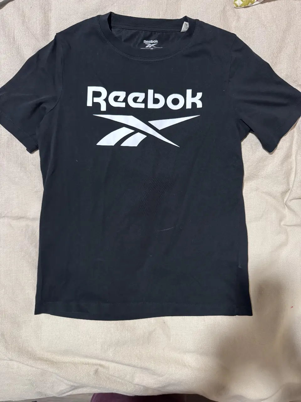 Remera deportiva Reebok negra con logo blanco. Talle S. Ideal para entrenar o uso casual.