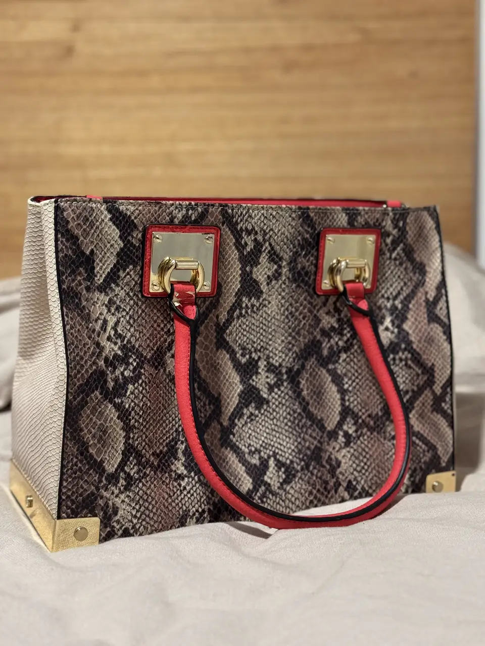 Cartera de mano con estampado de serpiente, detalles en rojo y dorado. Ideal para un look sofisticado. está nueva solo que del tiempo el cuero sintético se gasto