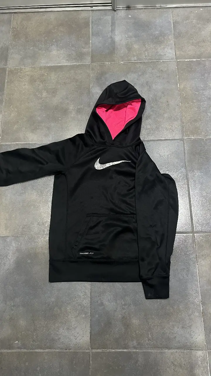 Buzo deportivo Nike Therma-Fit para niño, color negro con interior rosa. Con capucha y logo de la marca en blanco. Talle L.