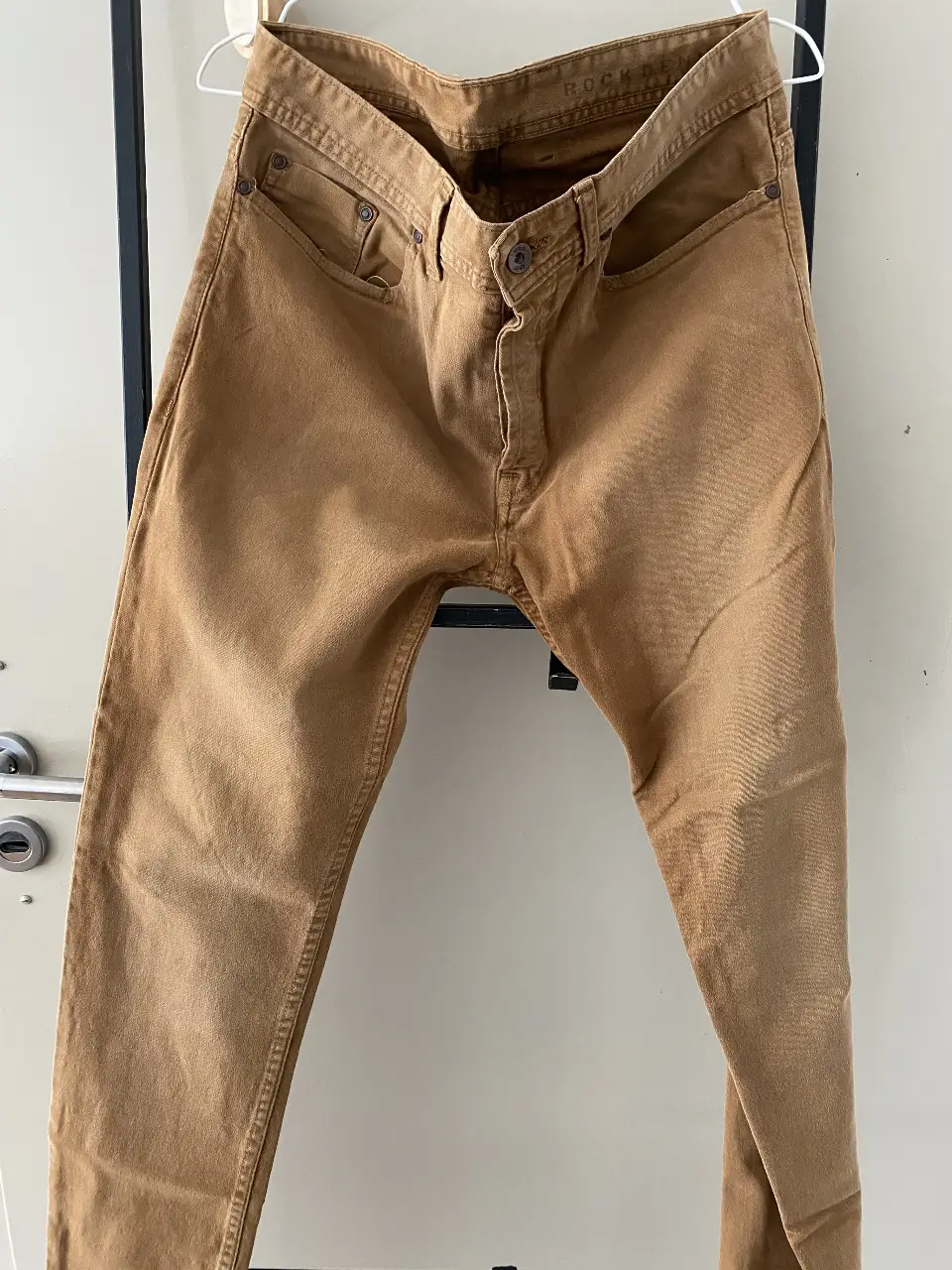 Jeans rectos color marrón, tiro medio, con detalles de costuras y bolsillos clásicos. Ideal para un look casual y versátil.