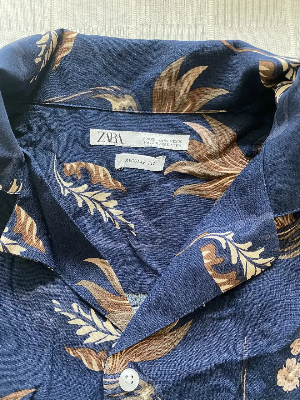 Camisa estampada de hombre, manga corta, con estampado floral en tonos azules y marrones. Corte regular fit, ideal para un look casual y fresco.