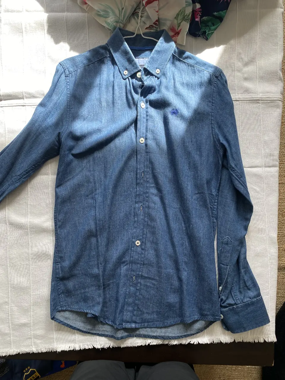 Camisa de hombre de jean azul, con un bordado en el pecho. Ideal para un look casual y moderno.