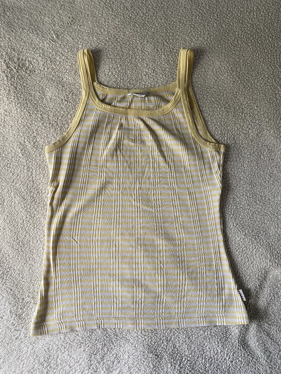 Musculosa a rayas amarillas y blancas, con cuello redondo y breteles anchos. Ideal para un look casual y fresco.