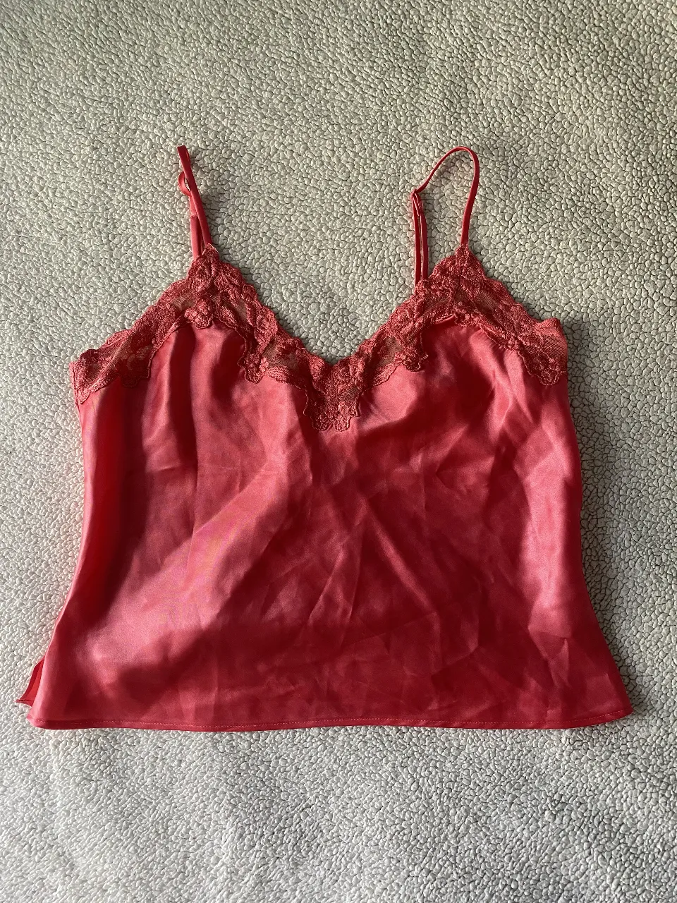 Top de satén rosa con detalles de encaje en el escote. Breteles finos regulables. Ideal para usar como lencería o para un look más audaz.