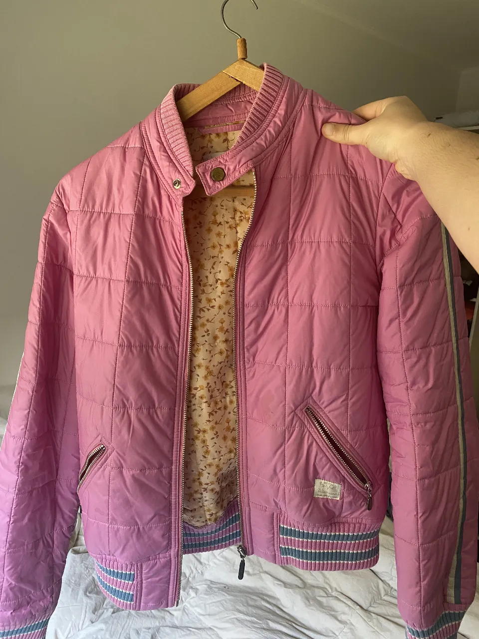 Campera bomber vintage acolchada rosa Wanama, con detalles en blanco y celeste. Cierre frontal y bolsillos con cierre. Interior con estampado floral. Ideal para un look casual y canchero.