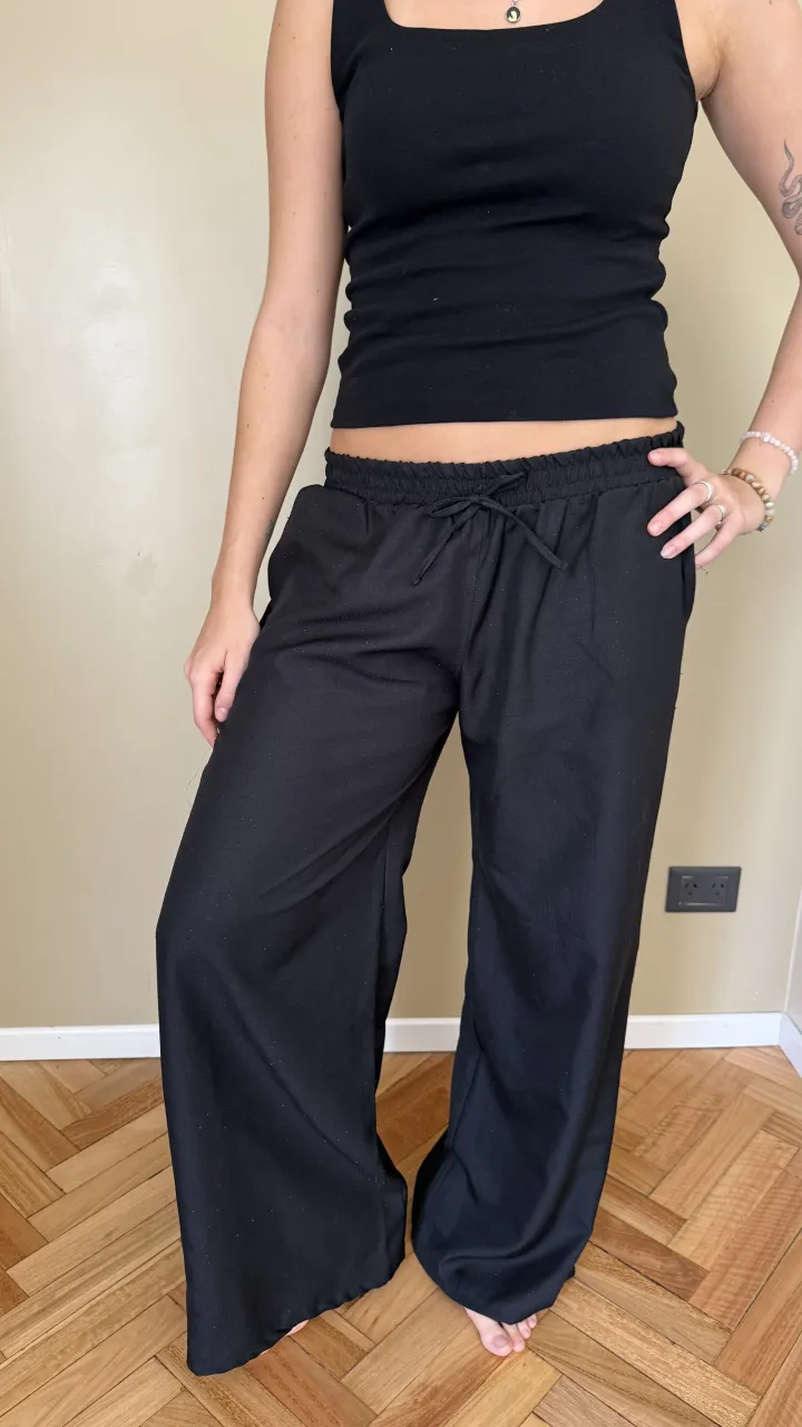 Pantalón negro ancho, tiro alto, con cintura elastizada y cordón ajustable. Ideal para un look cómodo y canchero, perfecto para el día a día o para estar relajada en casa.