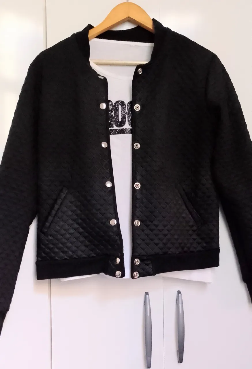 Campera bomber negra de matelasse con botones plateados y bolsillos delanteros. Liviana. Posee un diseño acolchado en rombos.