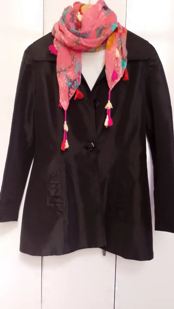Campera , saco piloto liviano,color negro de vestir, ideal para un look elegante y sofisticado. Posee un diseño entallado que realza la figura, con detalles de frunces en los bolsillos y botón al frente. Se complementa con un pañuelo estampado en tonos rosas y fucsias, con flecos que le dan un toque bohemio y divertido. Sin fallas ni detalles. Solo el saco está a la venta 