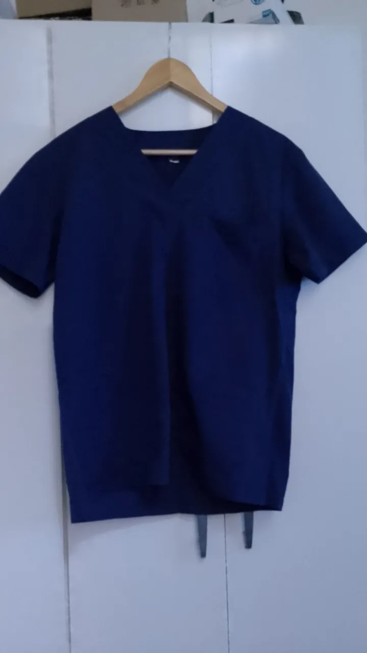 Ambo uniforme médico de color azul marino. Incluye una remera de manga corta con cuello en V y un bolsillo en el pecho, y un pantalón con cintura elástica y bolsillos. Tela tipo Arciel sin detalles de uso 