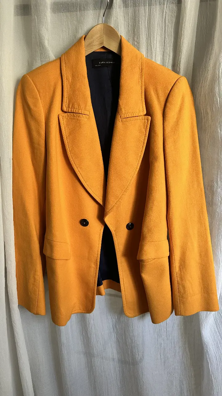 Blazer de mujer color naranja, de la marca Zara Woman. Confeccionado en paño, de corte clásico con dos botones y solapas. Ideal para un look elegante y moderno.