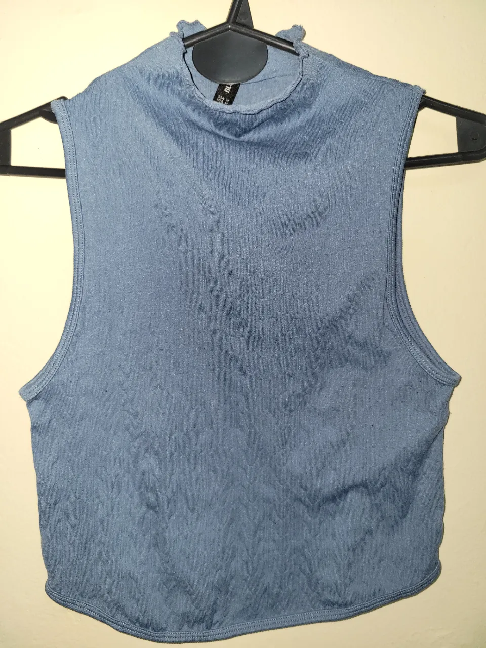 Top sin mangas de cuello alto en color azul. Ideal para un look moderno y versátil.