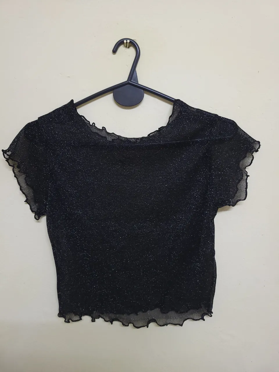 Top negro brillante con diseño de volados en el borde. Ideal para fiestas y salidas.