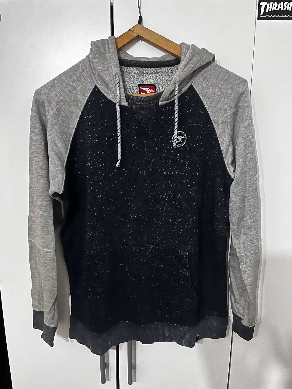 Buzo canguro para hombre, con capucha y bolsillo frontal. Diseño en dos tonos, gris en mangas y capucha, negro en el cuerpo. Ideal para un look casual y cómodo.