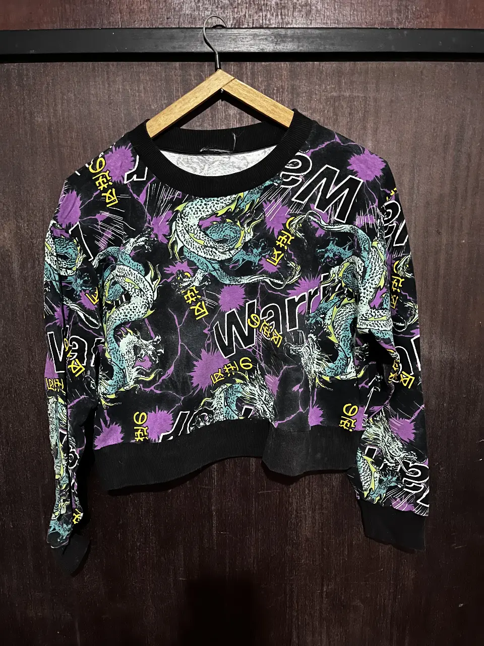 Buzo de cuello redondo con estampado de dragones y letras "WARRIOR". Estilo streetwear, ideal para un look casual y moderno.