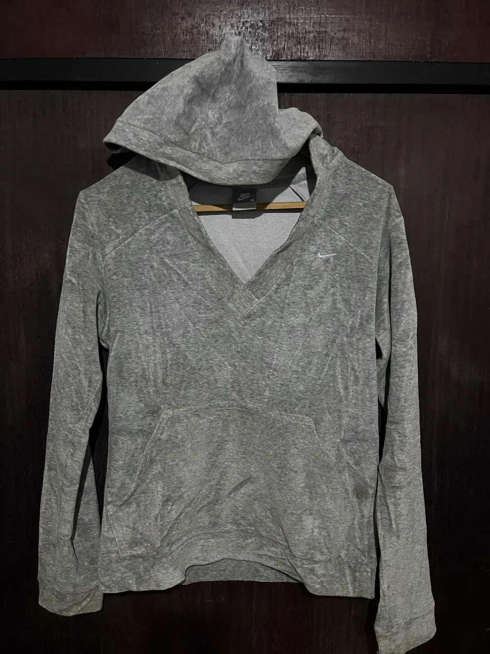 Buzo con capucha Nike gris, con cierre y bolsillo delantero. Talle M, ideal para un look casual y cómodo.