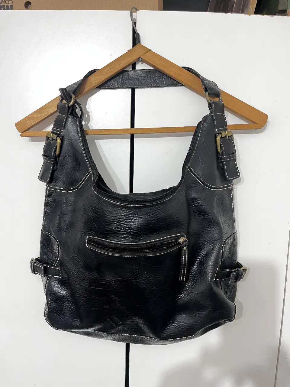 Cartera negra de hombro, con detalles de costuras blancas y hebillas decorativas. Ideal para un look casual y versátil.