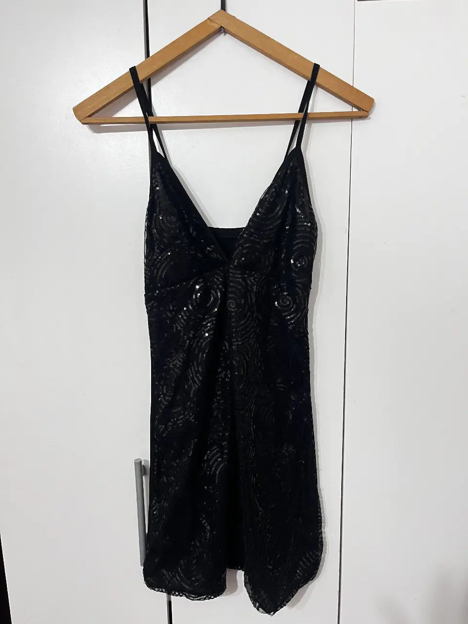 Vestido mini negro con lentejuelas, ideal para fiesta. Diseño con tirantes finos y escote en V.