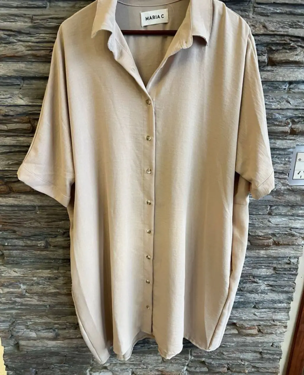 Camisa de manga corta holgada en color crudo, con botones frontales y cuello clásico. Ideal para un look casual y cómodo.