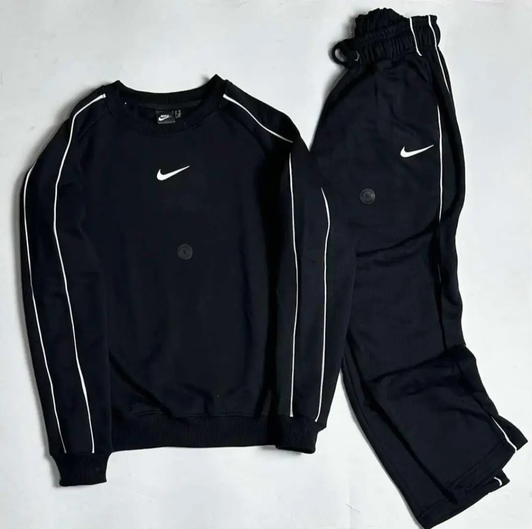 Conjunto deportivo Nike negro con detalles blancos. Buzo de cuello redondo y pantalón con cintura elastizada y logo de la marca.
