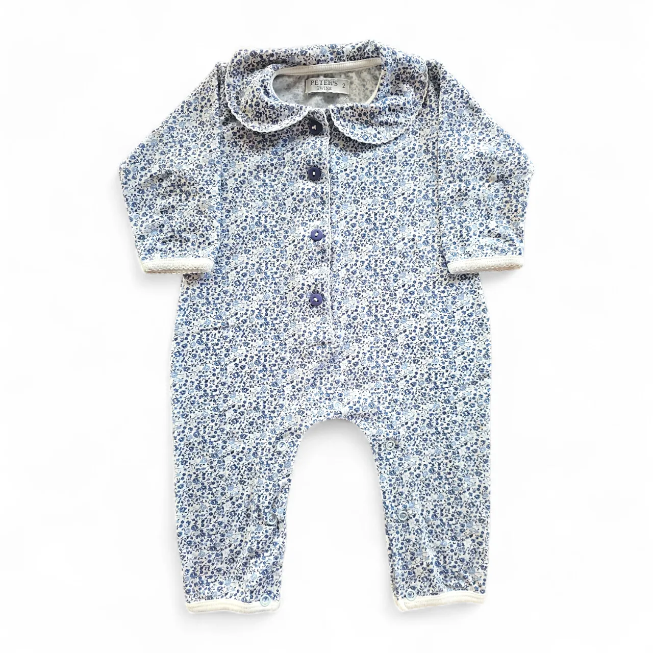 Enterito de bebé estampado floral en tonos azules y blancos. Posee cuello redondo con volados y botones al frente. Ideal para los días de entretiempo o para estar cómodo en casa.