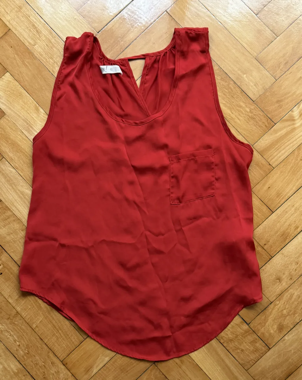 Musculosa roja con escote en V y un bolsillo en el frente y se abre en la espalda
