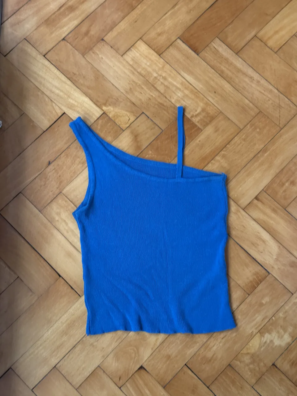 Top azul de un solo hombro, con tiritas finas y textura acanalada. Ideal para un look canchero y moderno.