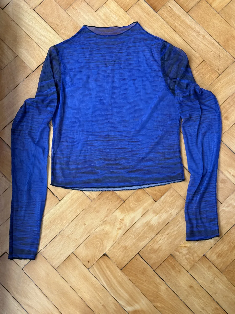 Remera manga larga azul con estampa abstracta en negro. Posee cuello redondo y es de tela transparente. Ideal para un look canchero y moderno.