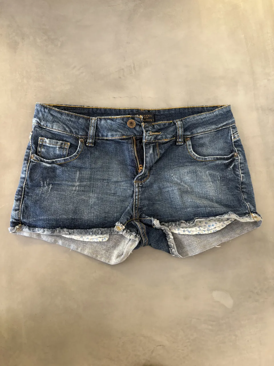 Shorts de jean Wanama tiro medio con roturas y detalles deshilachados en los bordes. Poseen un estampado floral sutil en el interior de los dobladillos. Es elastizado, la etiqueta dice 27 pero es más un 25/26. Tiene un solo uso.