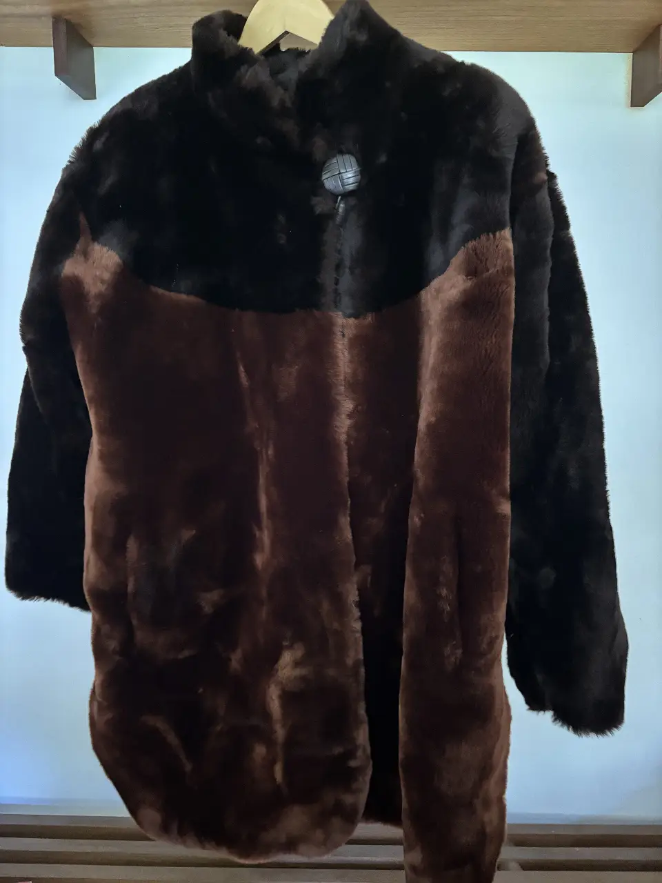 Tapado de piel de la marca Yves Saint Laurent, con diseño bicolor en marrón y negro. Posee un botón decorativo y un forro interior.
