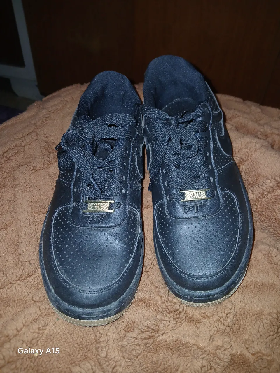 Zapatillas Nike Air Force 1 negras, con detalles dorados. Ideales para un look casual y urbano.