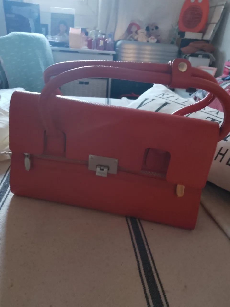 Cartera roja de mano, con manijas curvas y cierre metálico. Ideal para un look elegante y sofisticado.