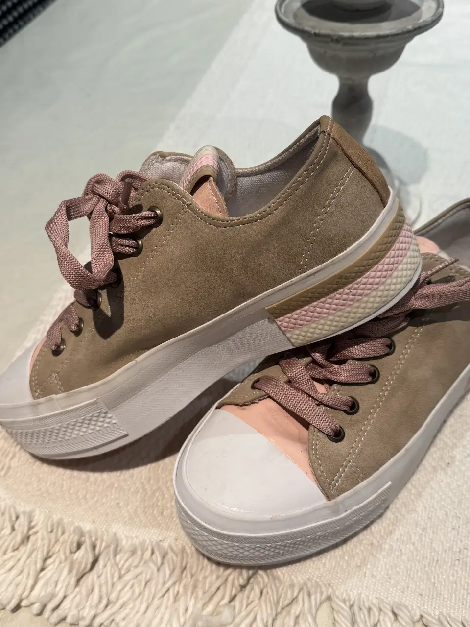 Zapatillas de lona color marrón con detalles en rosa y suela blanca. Ideales para un look casual y cómodo.