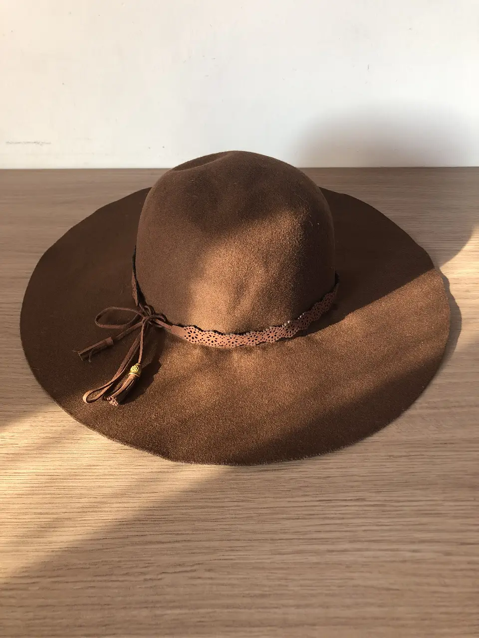 Sombrero de fieltro marrón con ala ancha y cinta decorativa. Ideal para un look bohemio y elegante. Perfecto para protegerte del sol con estilo.